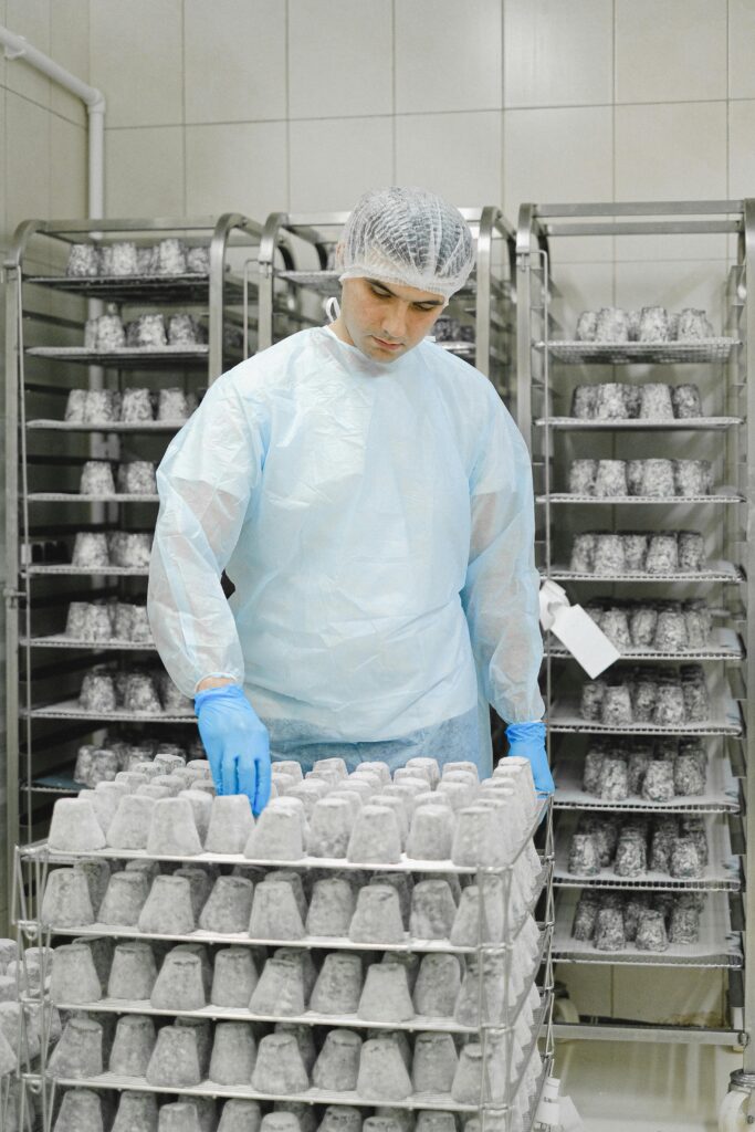 pexels-photo-5953752-5953752 A worker in hygienic clothing handling food storage in a production facility.