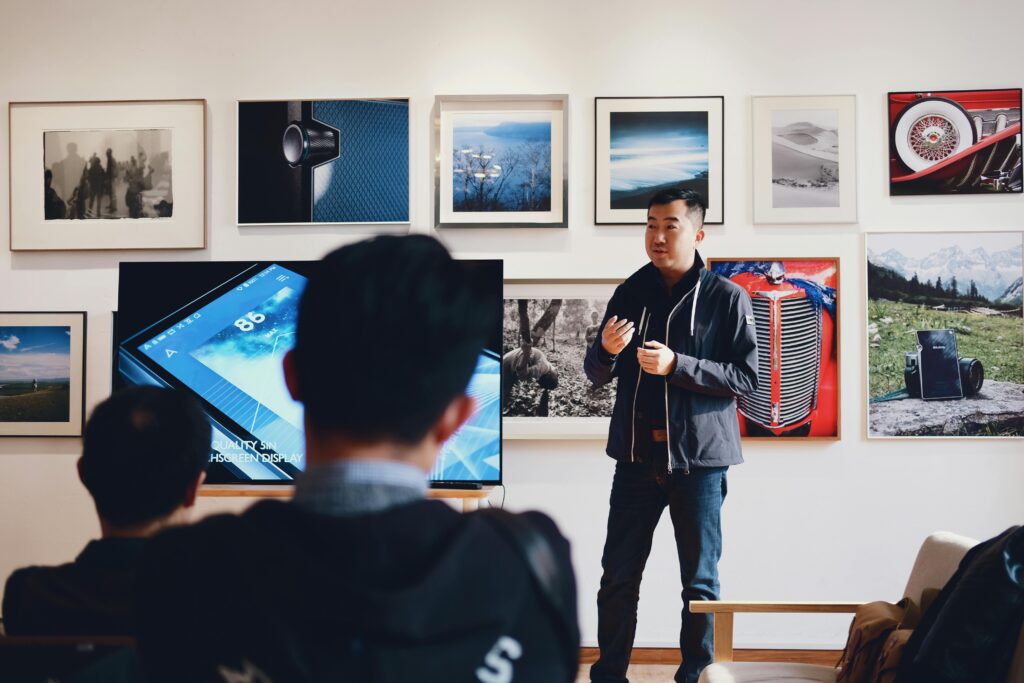 pexels-photo-716276-716276 Man giving a presentation in a modern art gallery setting, engaging audience.